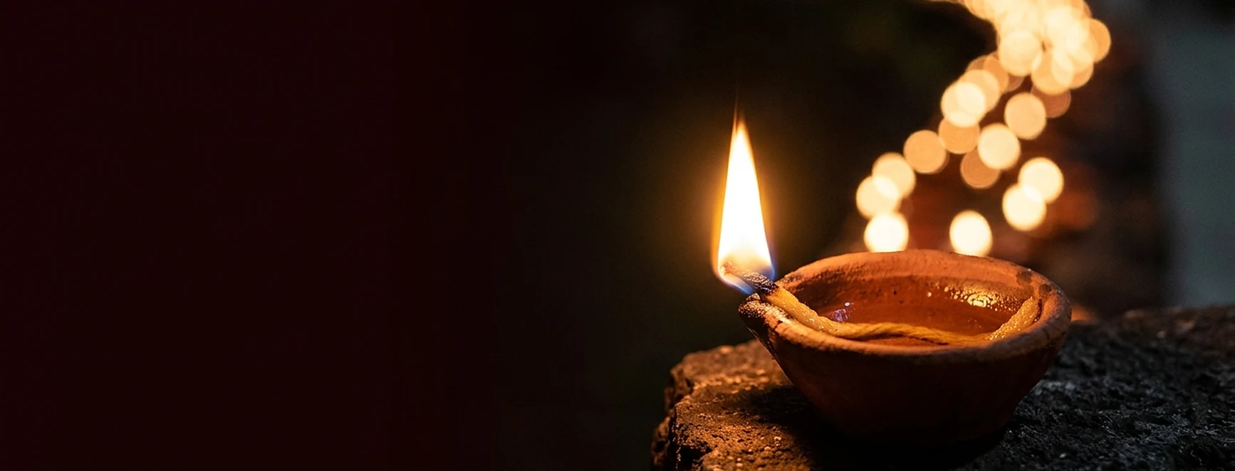 A lit clay diya glowing in the dark promotion